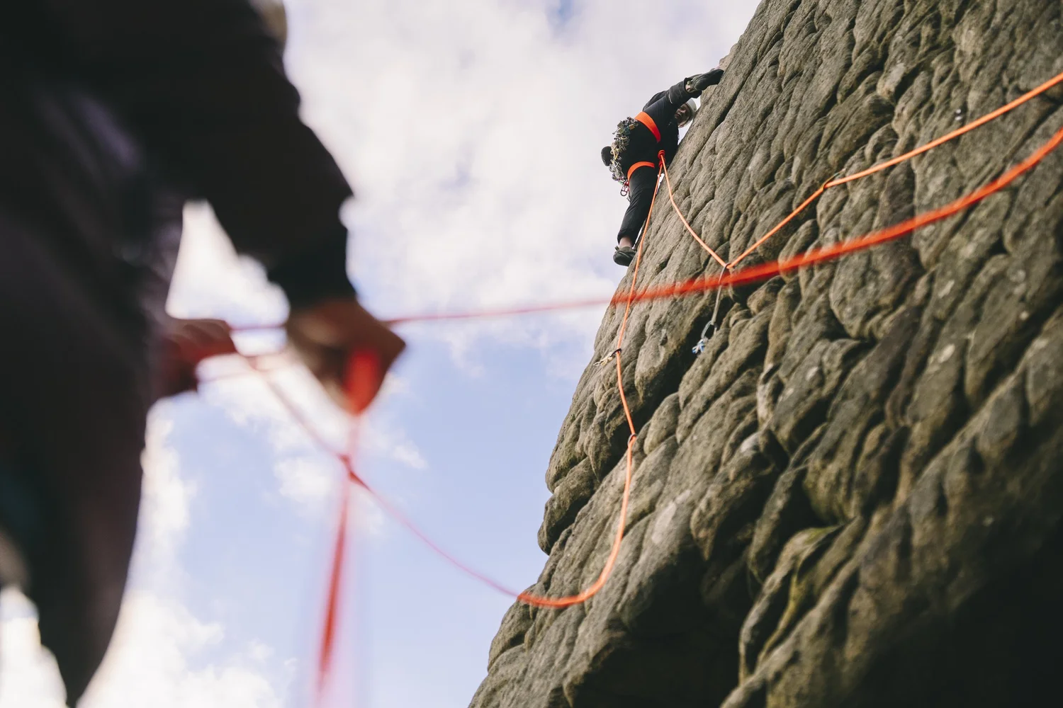 Climber on Stanage Edge with belayer below